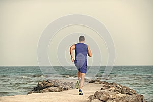Mens heals body care. Sportsman back view training outdoors on seascape
