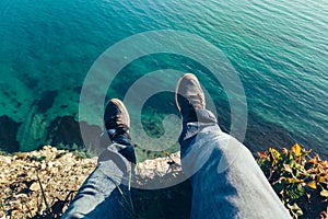 Mens legs in sneakers in background of picturesque sea landscapehiking travel relaxing concept