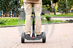 Mens legs on two-wheeled gyro against the background of city park, copy space