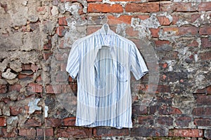 Mens light striped summer shirt hanging on a brick wall outdoors