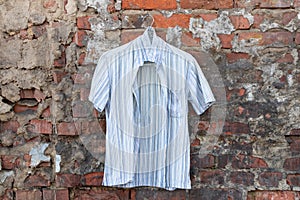 Mens light striped summer shirt hanging on a brick wall outdoors