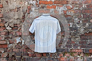 Mens light striped summer shirt hanging on a brick wall outdoors