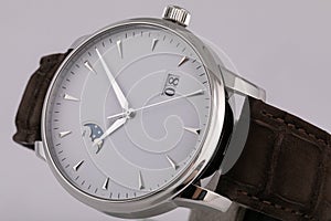 Mens silver watch with a white dial, golden clockwise, chronograph, with a black leather strap, isolated on white background.
