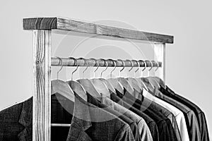 Mens suits in different colors hanging on hanger in a retail clothes store, close-up. Mens shirts, suit hanging on rack