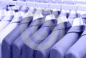 Mens suits on hanger in a store close up, concept color of the year 2022.