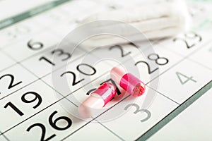 Menstrual calendar with pills and tampon, closeup