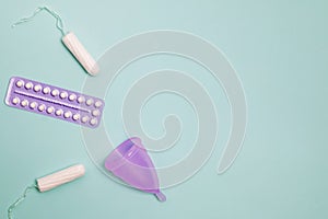 Menstrual cup, tampons and oral contraceptive tablets on pastel background, top view.