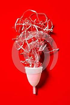Menstrual cup white and eco friendly isolated on a red background, concept photography for a women`s or feminist blog