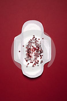Menstrual pad with glitter stars on red background