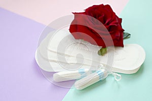 Menstrual pads and tampons with red rose flower on multicolored background