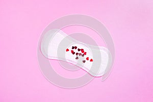 Menstrual daily sanitary pad with red hearts that mimic blood on pink background