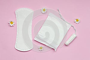 feminine hygiene and protection products, sanitary pads, tampon and chamomile flowers on pastel pink background, top view, flat la