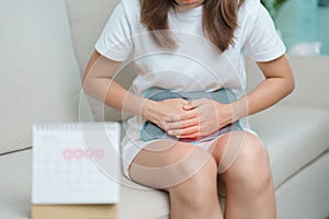 Menstruation period cycle of monthly and Stomachache concepts. woman having abdomen pain with hot water bottle and calendar,