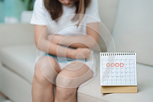Menstruation period cycle of monthly and Stomachache concepts. woman having abdomen pain with hot water bottle and calendar,