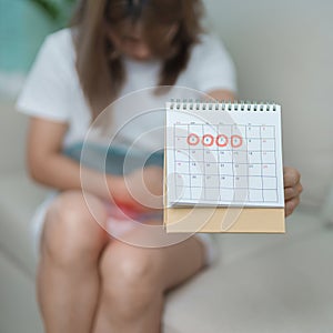 Menstruation period cycle of monthly and Stomachache concepts. woman having abdomen pain with hot water bottle and calendar,