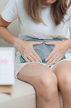 Menstruation period cycle of monthly and Stomachache concepts. woman having abdomen pain with hot water bottle and calendar,