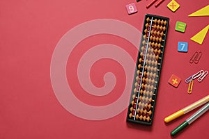 Mental arithmetic and math concept: colorful pens and pencils, numbers, abacus scores on red background, copy space