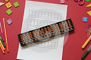Mental arithmetic and Mathematics concept: colorful pens and pencils, numbers, abacus scores on red background