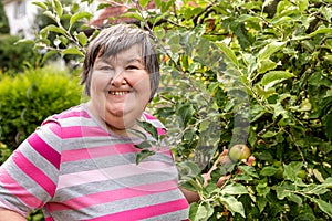 Mental disabled woman is showing a apple on a apple tree