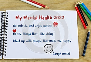 Mental health goals 2022 heading with list of ideas hand written in note book on desk