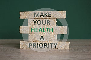 Mental health psychological symbol. Concept words Make your health a priority on brick blocks on a beautiful green background.