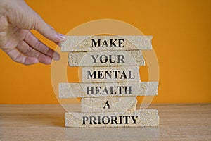 Mental health psychological symbol. Concept words Make your mental health a priority on brick blocks on a beautiful orange