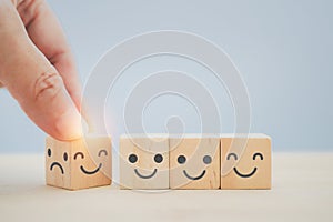 mental health, service mind concept, hand change bad temper face to good mood icon on wooden cube block with copy space