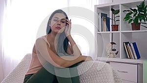 Mental health, sorrowful female in depression sitting on sofa in bright room at home