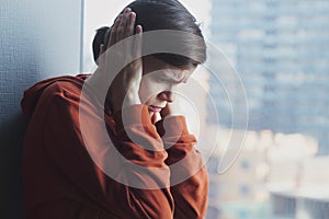 Young sad depressed frustrated autistic woman sitting at home alone suffering from head ache and psychological problems photo