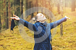 Mental health and stress relief during covid-19 pandemic. woman enjoying nature and fresh air with removed face mask in forest