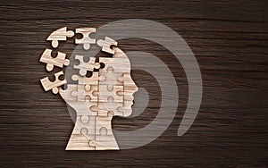 Mental health symbol. Human head silhouette with a puzzle cut out from wooden background