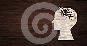 Mental health symbol. Human head silhouette with a puzzle cut out from wooden background