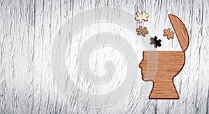 Mental health symbol. Human head silhouette with a puzzle cut out from wooden background