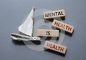 Mental Health symbol. Wooden blocks with words Mental Health is Health. Beautiful grey background with boat. Medical and Health