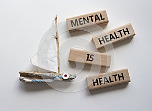 Mental Health symbol. Wooden blocks with words Mental Health is Health. Beautiful white background with boat. Medical and Health