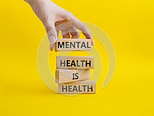 Mental Health symbol. Wooden blocks with words Mental Health is Health. Beautiful yellow background. Doctor hand. Medical and