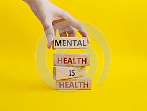 Mental Health symbol. Wooden blocks with words Mental Health is Health. Beautiful yellow background. Doctor hand. Medical and