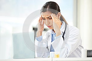 Mental health, woman doctor with headache and laptop at her desk in a modern office. Anxiety or stress, depression or