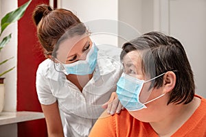 Mentally disabled woman and nurse or caretaker wearing a surgical mask, covid-19