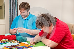 Mentally disabled woman and young man doing arts and crafts