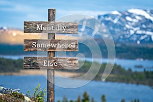 mentally somewhere else text on wooden signpost outdoors in landscape scenery during blue hour.