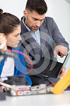 mentor and apprentice in workshop looking at laptop