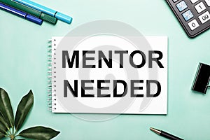 MENTOR NEEDED is written on a white sheet on a blue background near the stationery and the Scheffler sheet. Call to action.