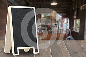 Menu board on wooden top table with blurred of coffee shop background