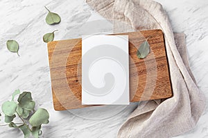 Menu card mockup on wood board with linen napkin on marble table