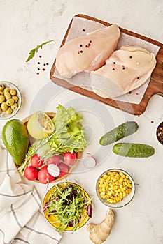 Menu fot Paleo, FODMAP diet concept. Fruits,vegetables, olives, chicken meat, greens on wooden cutting board. photo