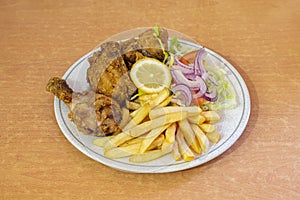 Menu plate with pieces of broaster chicken in batter with salad guarnicion with purple onion with lemon photo