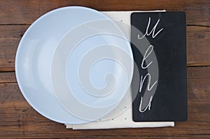 Menu written with chalk on aged blackboard with kitchen utinensil on wooden table