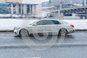 Mercedes Maybach S class car driving during a blizzard on the road. Winter, snow, slippery asphalt, poor visibility on the streets