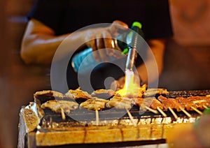 Merchant cook burning fire to roast pork skewer.
